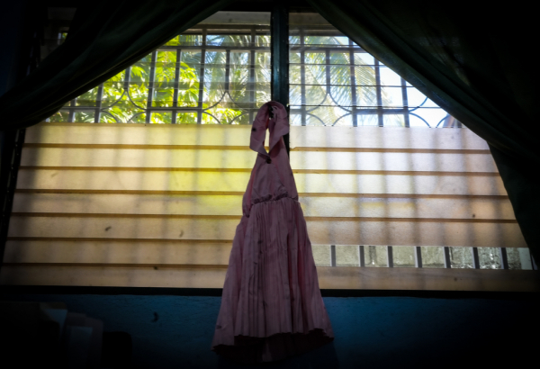 Um vestido infantil pendurado em uma das janelas da Kay ble. “Kay ble” (“Casa azul”, na língua crioula) é um dormitório localizado na clínica Pran Men’m, que oferece acomodação temporária de emergência para sobreviventes que não podem voltar para casa em segurança. Haiti. ©MSF