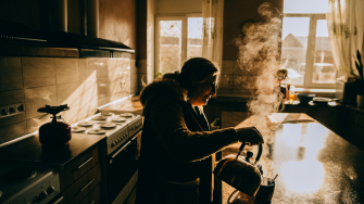 Yuliia Murashkina, deslocada pela guerra na Ucrânia, prepara o café da manhã para a sua neta. A família vive no abrigo em Dnipro com outras pessoas há quatro anos. A luz solar é a única disponível para os residentes, uma vez que não há eletricidade. ©Julia Kochetova