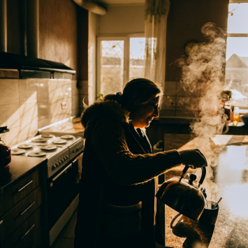 Yuliia Murashkina, deslocada pela guerra na Ucrânia, prepara o café da manhã para a sua neta. A família vive no abrigo em Dnipro com outras pessoas há quatro anos. A luz solar é a única disponível para os residentes, uma vez que não há eletricidade. ©Julia Kochetova