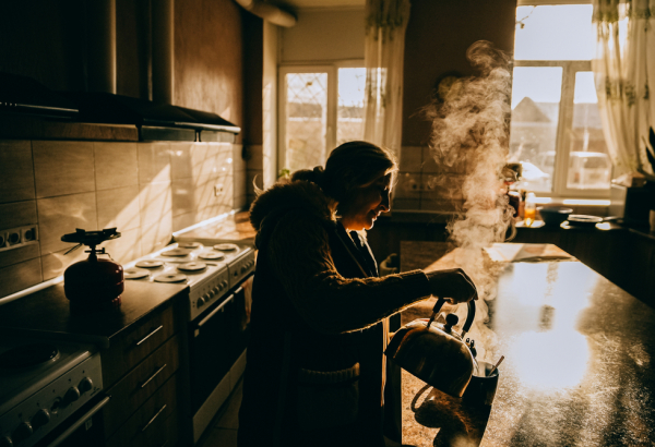 Yuliia Murashkina, deslocada pela guerra na Ucrânia, prepara o café da manhã para a sua neta. A família vive no abrigo em Dnipro com outras pessoas há quatro anos. A luz solar é a única disponível para os residentes, uma vez que não há eletricidade. ©Julia Kochetova