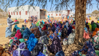 Pessoas deslocadas aguardam sob uma árvore para serem atendidas por profissionais de MSF no acampamento de Feina, no Sudão. Fevereiro de 2026. ©Julie Melichar