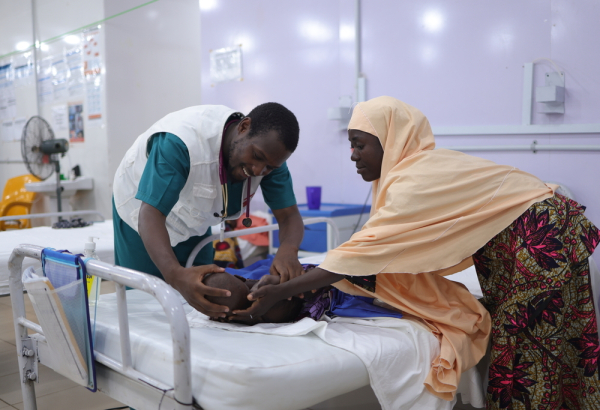 Profissional de MSF examina paciente em tratamento para desnutrição no no Centro de Internação para Alimentação Terapêutica em Katsina, na Nigéria. 2026. © Abba Adamu Musa/MSF