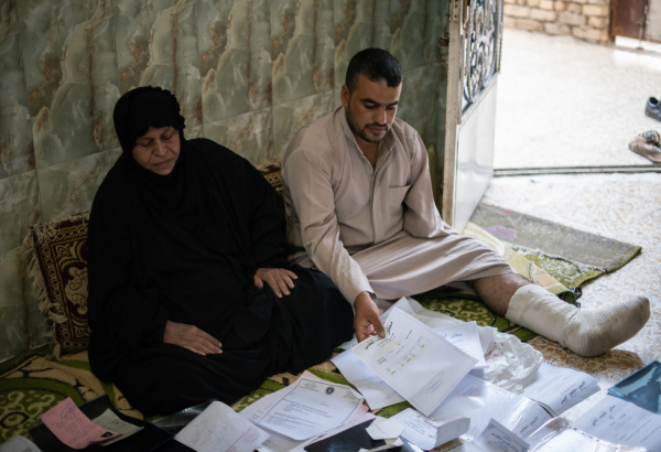 Hameeda e seu filho examinam seus arquivos médicos. Foto por: Chloe Sharrock / MSF