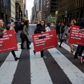 Pessoas atravessando faixa de pedestre carregando cartazes